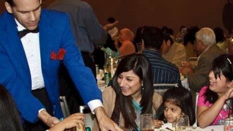 A magician entertains a group of women and children with a close-up magic trick at a Chicago event.