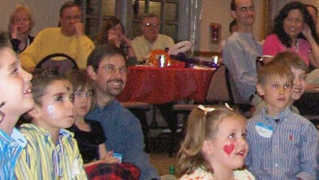 Children sitting on the floor, laughing and smiling, during a LIVE in-person performance of a birthday party magic show.