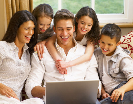 A family gathered around a laptop participating in a LIVE streaming 1-on-1 birthday magic show video call.